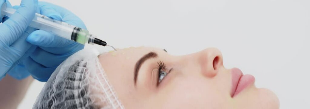 Close-up of a cosmetologist performing a facial peel on a young woman. Concept of professional care, rejuvenation, and healthy skin. Shot on anamorphic lens in 2.39
