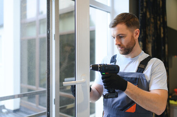 Worker installing plastic window indoors.