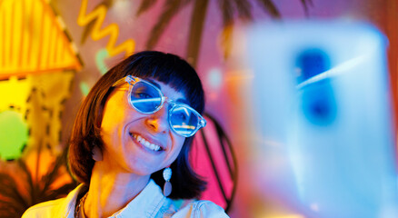 girl at a party. Portrait of a young girl in fashionable glasses taking a selfie using her phone at a party.