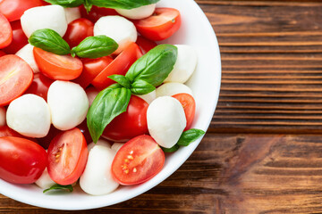 Basil leaves , cherry tomatoes and mozzarella cheese . In bowl food photography