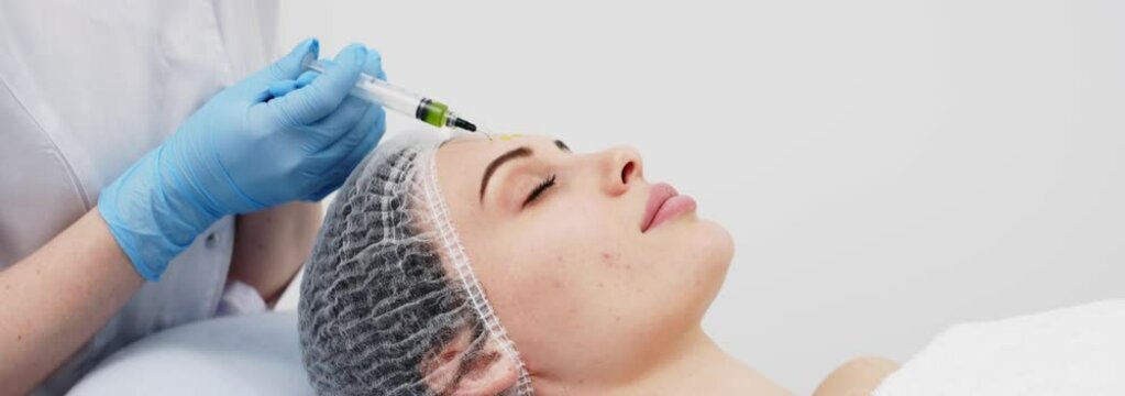 Close-up of a cosmetologist performing a facial peel on a young woman. Concept of professional care, rejuvenation, and healthy skin. Shot on anamorphic lens in 2.39