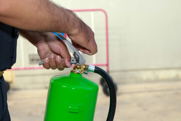 A person operates a green fire extinguisher, preparing for potential fire emergencies with careful...