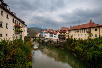 Obraz premium Captivating skofja loka reflecting on sorska river under cloudy sky