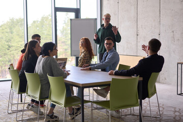 A young, diverse business team sitting together in a modern office, exchanging ideas and business plans, fostering collaboration and innovation for future success.