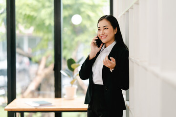 Fototapeta premium Cheerful businesswoman using smartphone to chat at office