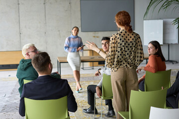 A diverse group of business professionals sits attentively in a modern office, actively...