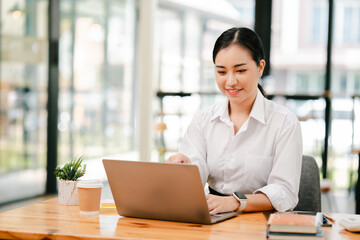 Asian female student studying online and taking notes. Female accountant doing annual financial and tax reports