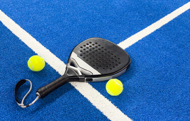 Black professional paddle tennis racket and ball on blue background. Horizontal sport theme poster,...