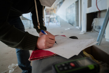 A close-up of an engineer's hand meticulously sketching an architectural project, capturing the...