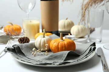 Rustic holiday table setup with plates, cutlery and autumn decorations