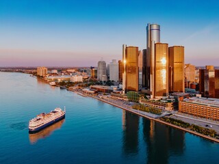 Detroit skyline at sunrise, cruise ship on the river. Iconic GM headquarters reflected in the...