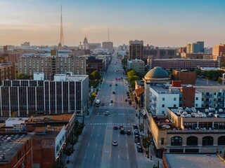 Aerial view of a city street at dawn. Cars and pedestrians navigate the urban landscape. Buildings...