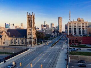 City street scene at dawn, Detroit, MI. Traffic flows through downtown, past historic church. Urban landscape. DOWNTOWN, DETROIT, MICHIGAN, UNITED STATES