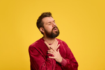 Obraz premium Young man feels badly, first symptom of sickness sore throat against yellow studio background. Epidemic. Concept of healthcare, medicine, infection and treatment. Ad.