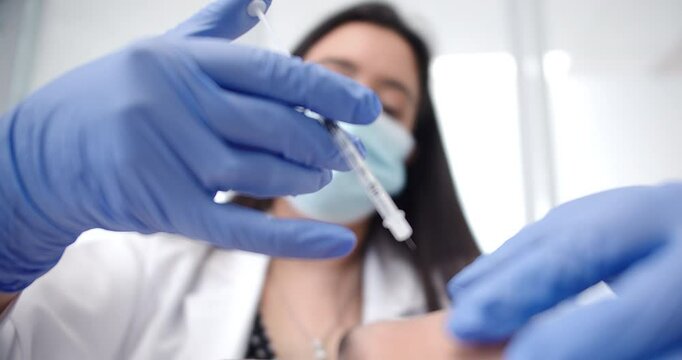Amazing slow motion shot of a dermatologist doctor injecting Botox into a patient's forehead at a clinic during a beauty treatment.