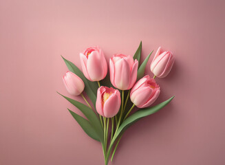 Fototapeta premium A small bouquet of light pink tulips arranged on a blush pink background. The image is simple and elegant, perfect for a greeting card or spring-themed design.