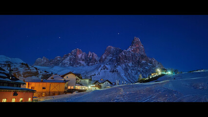 Passo Rolle e le Pale di San Martino durante il panorama notturno con cielo stellato e paesaggio invernale innevato