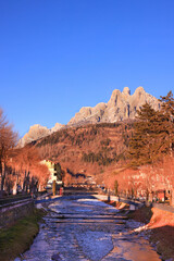 Primiero e le Pale di San Martino viste dal paese durante il tramonto con luci calde e cielo blu