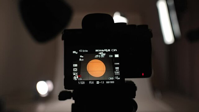 Professional studio for photo video filming with lighting and large cyclorama background, pov from camera on tripod with live viewfinder screen with live recording.