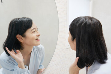 鏡を見てヘアセットする50代の女性