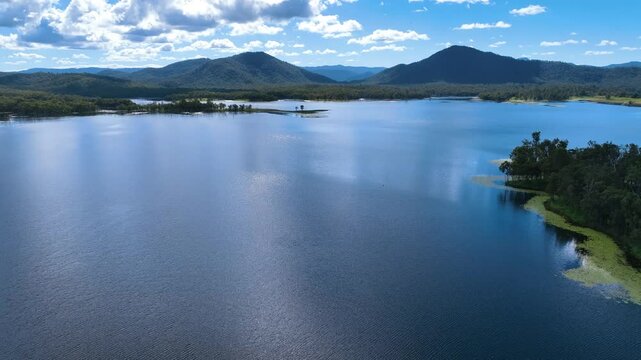 Relaxing aerial descends to the shimmering waters of Central Queenland's Lake Teemburra weir under a bright sunny day Australia