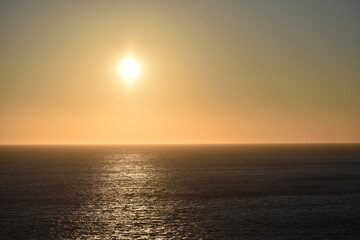 Golden sunset over the vast ocean with light reflecting on the calm water The serene scene captures the beauty of the horizon as the day transitions into night
