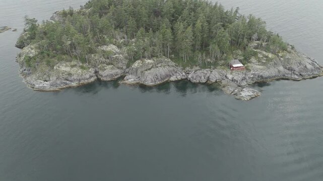 Drone footage of a an islet covered with green vegetation off the Sunshine Coast in Gibsons, Canada