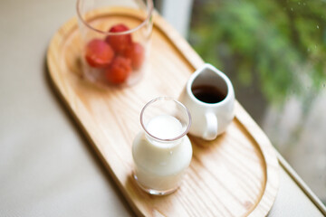 Strawberry ice cubes with a jar of milk and a cup of espresso on a wooden tray. Preparation for making strawberry latte.