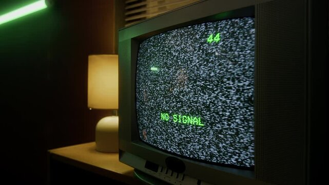 Close-up of vintage CRT television with no signal message in green text on channel 44 in dimly lit room with green neon light