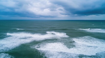 Serene Ocean Waves Under Dramatic Cloudy Sky with Gentle Ripples and Foamy Crests Captured from Above in a Tranquil Seascape View