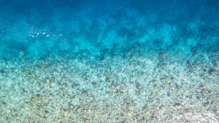 Top view of the turquoise gradient color of the water. The ocean is like a background. Incredible gradient from light blue to dark. Reef and fish swim. Clear water in the lagoon. The drone. Maldives