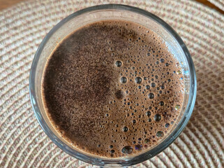 A close-up view of a coffee cup filled with rich, frothy coffee, emphasizing the texture and bubbles on the surface. Perfect for coffee lovers and food photography enthusiasts.
