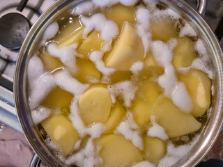 Fresh potatoes boiling in a pot, creating bubbles and steam. A cooking process capturing the essence of home meals and culinary activities.