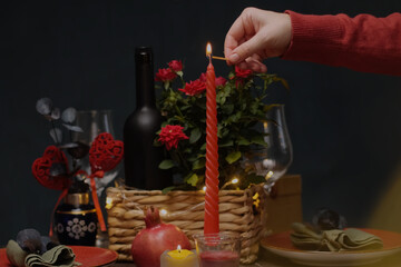 Romantic candlelight dinner table setting. Hand lights a candle on festive table for Valentine's Day.