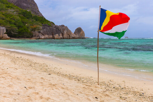 The flag of Seychelles stands on the beach