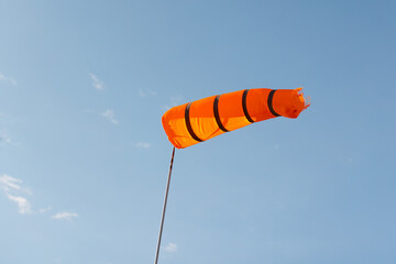 Windsock. Striped red wind indicator is under blue sky