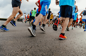 three runners behind large group people running city marathon