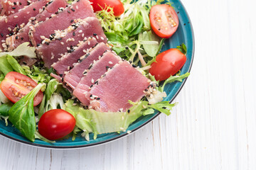 Salad with raw tuna , sesame and cherry tomatoes photography . Top view