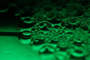 Green bubbles, fantastic liquid connections, fluid movement, dark fantastic background, transparent oil bubbles, chemical reactions
