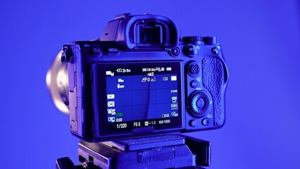 Professional studio for photo and video production filming with modern equipment, close up shot of details, camera on tripod in blue neon light.