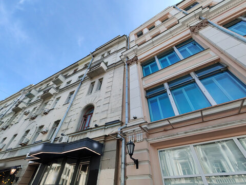 large multi-story building with a classic facade featuring arched windows and modern retail spaces on the ground floor. The blend of traditional architecture and urban commercial life reflects the