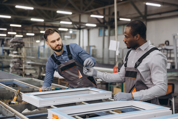 Factory workers assembling PVC windows in production line