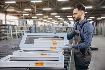 Factory worker checking aluminum and pvc window frames on production line