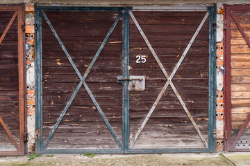 Wooden garage door with metal fittings, a lock and the number twenty-five. Background.