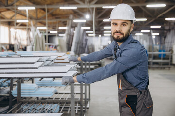 Factory worker moving aluminum profiles for windows and doors production