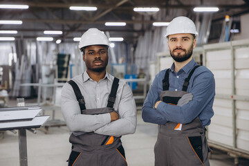 Factory workers posing with crossed arms in aluminum and pvc windows and doors production plant