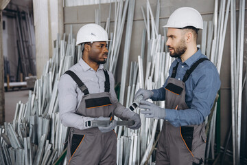 Factory workers discussing aluminum profiles for windows and doors production