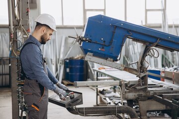 Factory worker operating industrial machine producing aluminum and pvc windows and doors