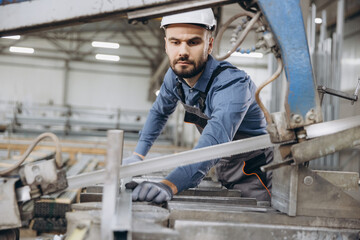 Factory worker cutting aluminum profiles for windows and doors production