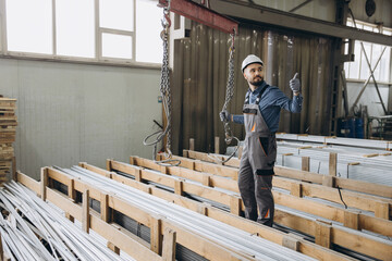 Factory worker handling aluminum profiles for windows and doors production